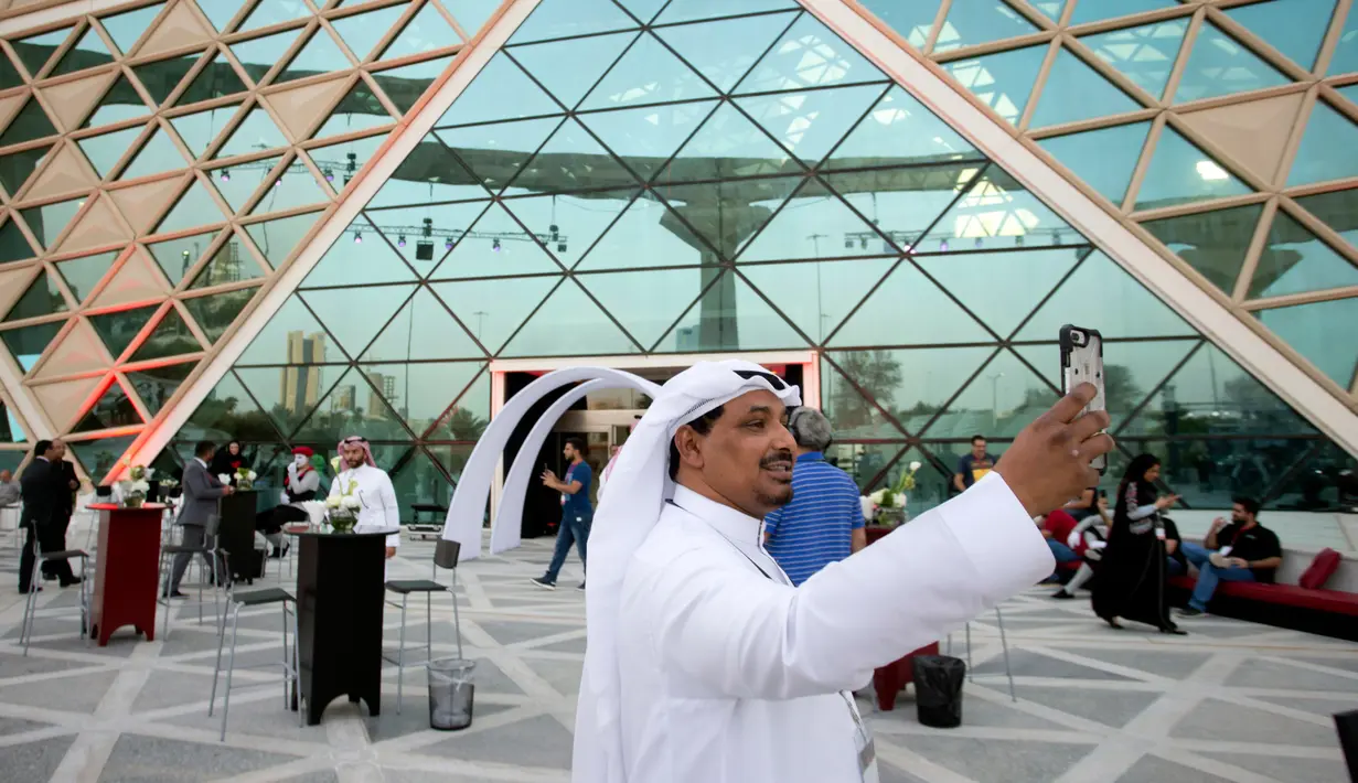 Pengunjung berswafoto dengan latar belakang teater bioskop pertama di King Abdullah Financial District Theatre, ibu kota Riyadh, Rabu (18/4). Peluncuran perdana bioskop Arab Saudi ini dihadiri oleh para tamu undangan. (AP/Amr Nabil)