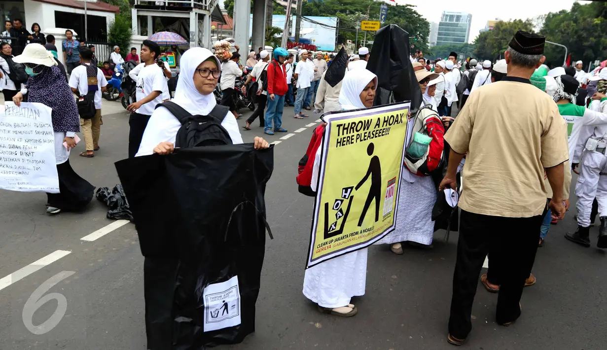 Sejumlah relawan membawa kantong plastik besar dan spanduk bertuliskan "Throw A HOAX, Here Please" di tengah aksi damai 4 November di Jakarta, Jumat (4/11). Mereka mengumpulkan sampah yang dibuang anggota ormas. (Liputan6.com/Faizal Fanani)