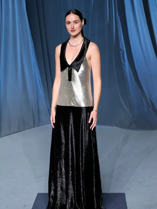 <p>Aktris Renate Reinsve tampil memesona dalam gaun tanpa lengan berwarna hitam dan perak dengan detail bordir yang rumit serta potongan leher deep polo neckline yang menambah kesan anggun dan modern. Ia memadukan tampilannya dengan sepatu hak satin hitam serta perhiasan dari koleksi Le Damier de Louis Vuitton Fine Jewelry, termasuk kalung, cincin, dan gelang dari emas putih bertabur berlian. [Dok/Louis Vuitton].</p>