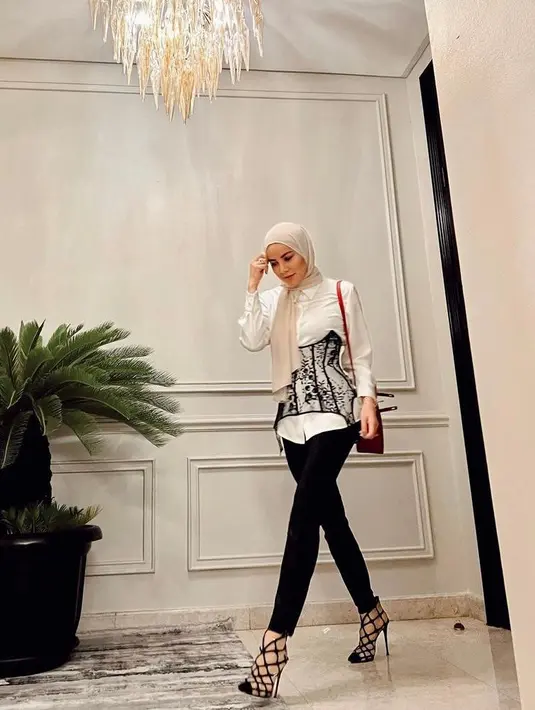 <p>Tampil elegan dengan padu padan kemeja putih, korset bordir, dan skinny jeans hitam. Untuk hijab, kamu bisa pilih warna krem agar tampak lebih trendi. (Instagram/ollaramlan).</p>