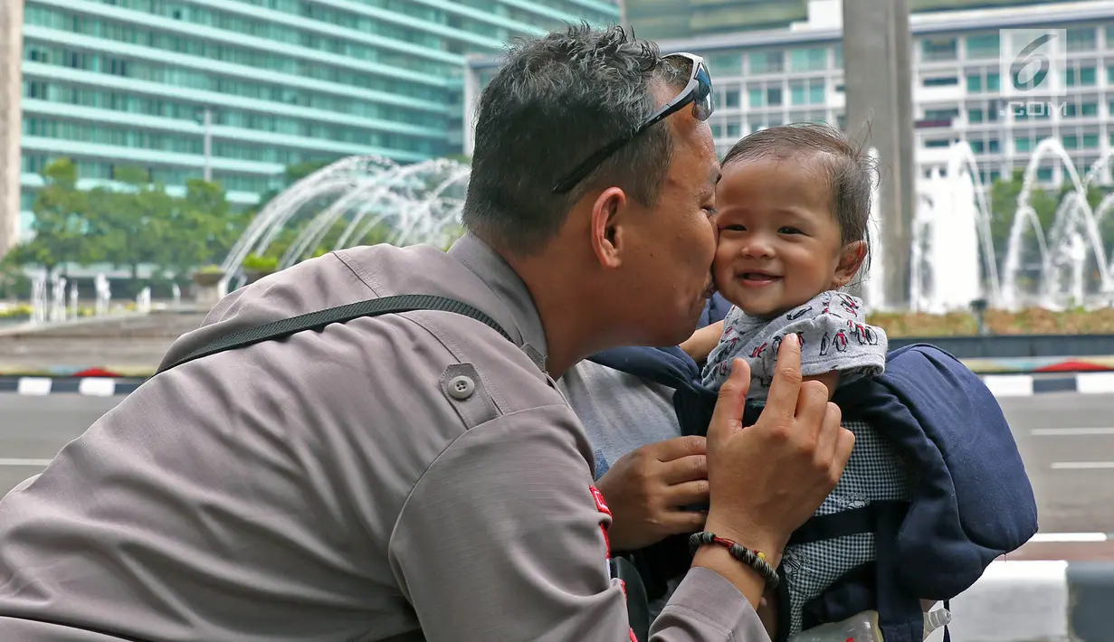 Brigpol Inardi Susanto mencium keponakan yang mengunjunginya di kawasan Bundaran HI, Jakarta, Minggu (9/6/2019). Anggota Polres Tarakan  ini sudah sebulan bertugas di Jakarta untuk mengamankan Ibu Kota pasca pelaksanaan Pemilu 2019.  (Liputan6.com/Herman Zakharia)
