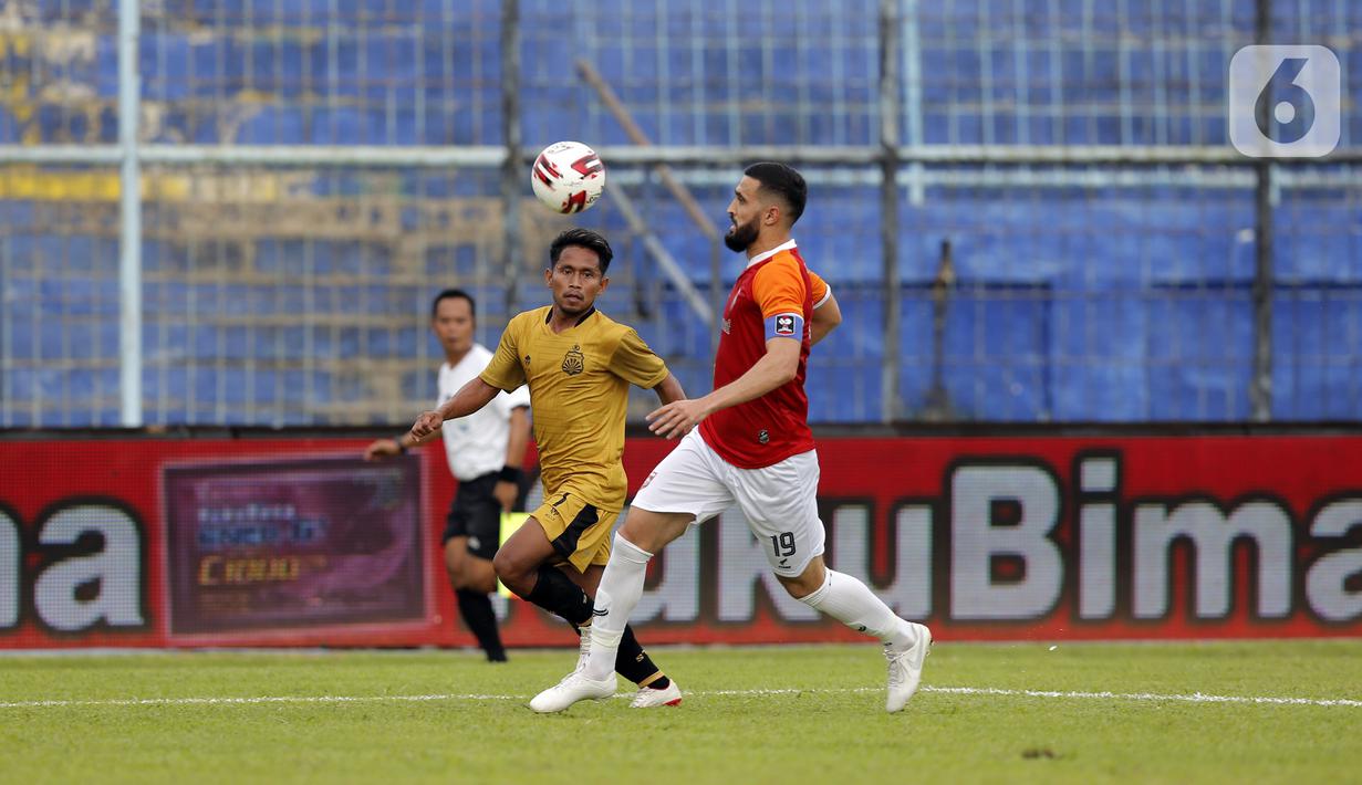 Pemain Borneo FC Samarinda Javlon Guseynov berusaha menghalau bola tembakan pemain Bhayangkara Solo FC Andik Vermansah dalam pertandingan babak penyisihan Piala Menpora 2021 di Stadion Kanjuruhan, Malang, Jawa Timur, Senin (22/3/2021). (Bola.com/Arief Bagus)