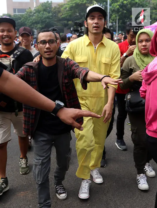  Aktor Abimana berjalan usai membagikan kopi gratis kepada pengunjung Car Free Day saat promo film Warkop DKI Reborn part 2 di Senayan, Jakarta, Minggu (13/08) (Liputan6.com/Fery Pradolo)