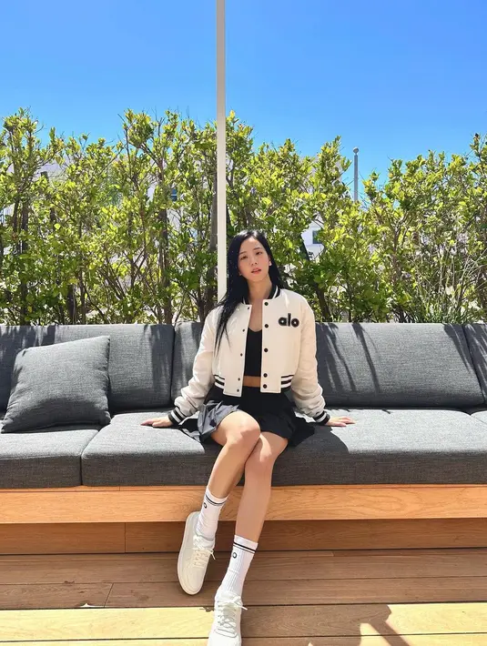 Padu padan cropped varsity jacket, crop top, dan rok tenis beri kesan manis pada penampilan Jisoo. Ia pun melengkapi gayanya dengan kaus kaki dan sneakers. [@sooyaaa__].