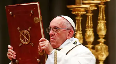 Paus Fransiskus memegang kitab Injil saat memimpin misa Natal di Basilika Santo Petrus, Vatikan, (24/12). Pada misa tersebut, Paus mengatakan bahwa Natal sudah "disandera" oleh materialisme. (REUTERS/Tony Gentile)