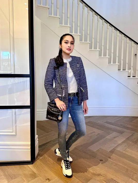 Sandra Dewi mengenakan kaus putih yang ditumpuknya dengan tweed blazer bernuansa biru. Dipadunya penampilan ini dengan belt hitam dan celana jeans. Foto: Instagram.