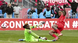 Penyerang timnas Kanada Cyle Larin mencetak gol melewati kiper Jamaika Andre Blake pada laga Kualifikasi Piala Dunia 2022 Zona CONCACAF di Venue BMO Field, Senin (28/3/2022) dini hari WIB. Kanadalolos ke Piala Dunia 2022 usai melibas Jamaika dengan skor 4-0 (Nathan Denette/The Canadian Press via AP)