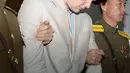 Mahasiswa University of Virginia, Otto Frederick Warmbier (tengah) saat digelandang oleh petugas keamanan Korea Utara di Pyongyang, (16/3). Ia didakwa karena sengaja mencuri pamflet berisi pesan propaganda pemerintah Korut di hotelnya. (REUTERS / Kyodo)
