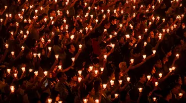 Umat Kristen memegang lilin saat ibadah malam Natal di Gereja Bethany, Surabaya, Jawa Timur, Minggu (24/12/2023). Pelaksanaan ibadah malam Natal berjalan aman dan lancar. (Juni KRISWANTO/AFP)