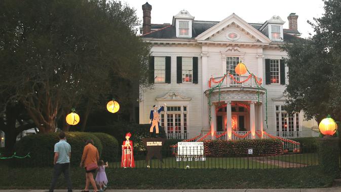 Para pejalan kaki melihat dekorasi Halloween di depan sebuah rumah di New Orleans, Louisiana, Amerika Serikat, pada 10 Oktober 2020. Tiga pekan sebelum perayaan Halloween, warga New Orleans mulai mendekorasi rumah mereka untuk menyambut festival tersebut. (Xinhua/Lan Wei)