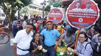 Dua anggota Kagama Solo Raya mengenakan tpeng berwajah Jokowi saat pembagian nasi tumpeng di Pasar Gede Solo, Kamis (17/10).(Liputan6.com/Fajar Abrori)