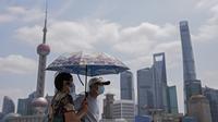 Sepasang warga yang mengenakan masker memegang payung saat mereka berkunjung ke Shanghai Bund di Shanghai, China, Senin (23/8/2021). Untuk pertama kalinya sejak Juli lalu, Otoritas Kesehatan China pada Senin (23/8) melaporkan nol kasus corona Covid-19 penularan lokal. (AP/Andy Wong)