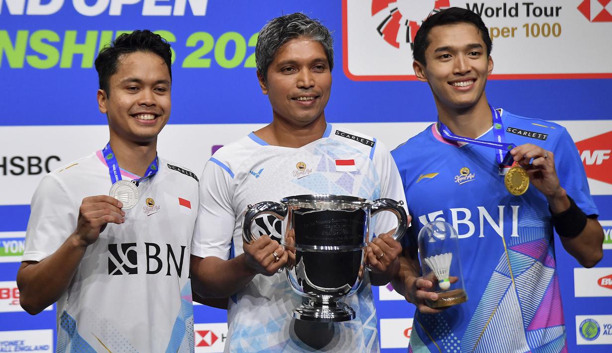 Juara tunggal putra kejuaraan bulu tangkis All England 2024, pebulu tangkis Indonesia, Jonatan Christie (kanan) dan rekan senegaranya sebagai runner-up, Anthony Sinisuka Ginting (kiri) berfoto bersama pelatih mereka, Irwansyah usai upacara penyerahan medali dan trofi di Utilita Arena, Birmingham, Inggris (17/3/2024) malam WIB. (AP Photo/Rui Vieira)