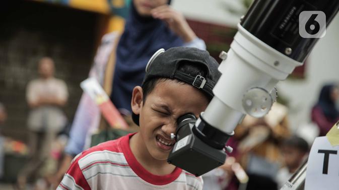 Pengunjung mengamati gerhana matahari cincin menggunakan teleskop di Planetarium Taman Ismail Marzuki, Jakarta, Kamis (26/12/2019). Planetarium menyediakan sekitar 10 teleskop dan kacamata khusus agar pengunjung bisa menyaksikan gerhana matahari cincin dengan aman. (Liputan6.com/Faizal Fanani)