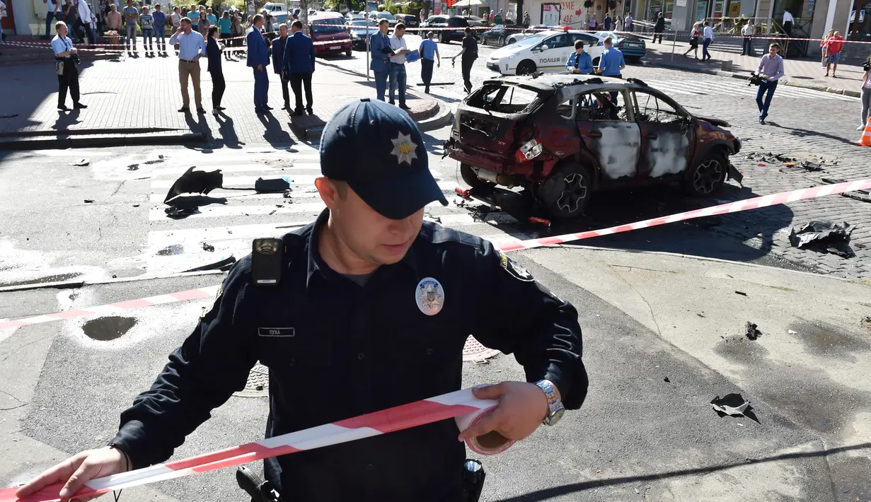 Petugas memasang garis polisi di dekat lokasi tewasnya jurnalis investigasi ternama, Pavel Sheremet di Kiev, Rabu (20/7). Jurnalis Ukrayina Pravda itu sedang mengendarai mobil ke tempat kerja ketika mobil tersebut meledak (Sergei SUPINSKY/AFP)