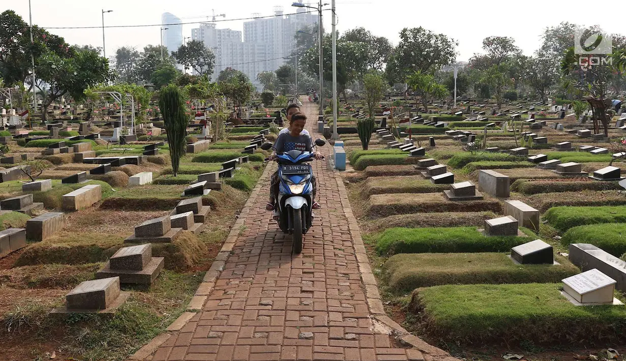 Dua anak menggendarai motor di sekitar TPU Karet Bivak, Jakarta, Kamis (26/7). Wagub DKI Jakarta Sandiaga Uno menyatakan Pemprov DKI akan mencari dan memerbanyak area TPU di Ibukota. (Liputan6.com/Immanuel Antonius)