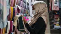 Pekerja mengenakan masker sebagai tindakan pencegahan penyebaran Covid-19 merapikan kerudung menjelang Idul Fitri yang menandai berakhirnya bulan suci Ramadan di Kuala Lumpur (13/5/2020). (AFP/Mohd Rasfan)