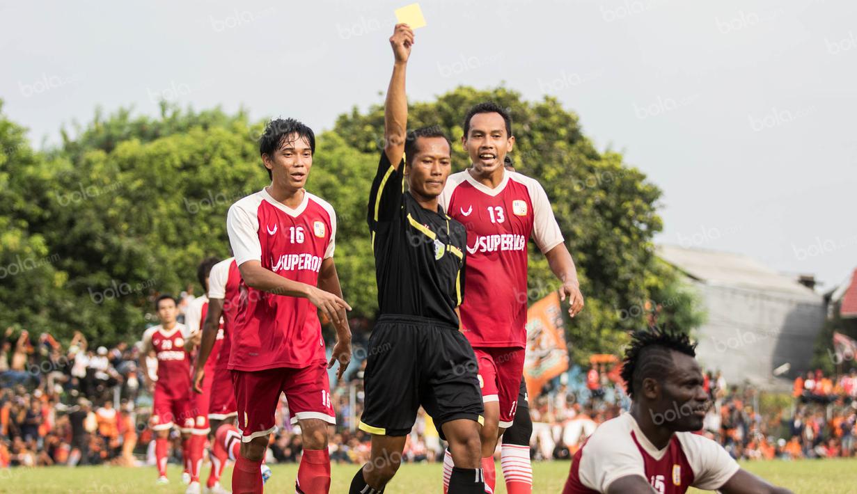 Wasit memberikan kartu kuning kepada bek Barito Putera karena melanggar pemain Persija pada laga ujicoba di Stadion Bea Cukai, Jakarta, Selasa (5/4/2016). Kedua tim bermain imbang 2-2. (Bola.com/Vitalis Yogi Trisna)