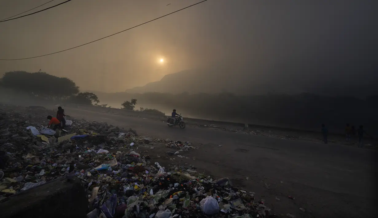 Anak-anak tunawisma mengumpulkan sampah untuk dijual kembali saat kebakaran besar melanda tempat pembuangan sampah Ghazipur di New Delhi, India (28/3/2022). (AP Photo/Manish Swarup)