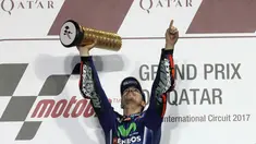 Pembalap Movistar Yamaha MotoGP, Maverick Vinales, mengangkat pialanya di atas podium setelah memenangi MotoGP Qatar di Sirkuit Losail, Doha, Minggu (26/3). Vinales menyelesaikan balapan dengan catatan waktu 38 menit 59,999 detik. (Karim JAAFAR/AFP)