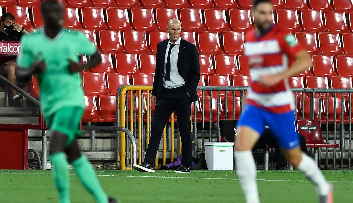 Pelatih Real Madrid, Zinedine Zidane (tengah) melihat pemainnya bertanding melawan Granada pada pertandingan lanjutan La Liga Spanyol di stadion Nuevo Los Carmenes di Granada (13/7/2020). Madrid menang tipis 2-1 atas Granada. (AFP/Jorge Guerrero)