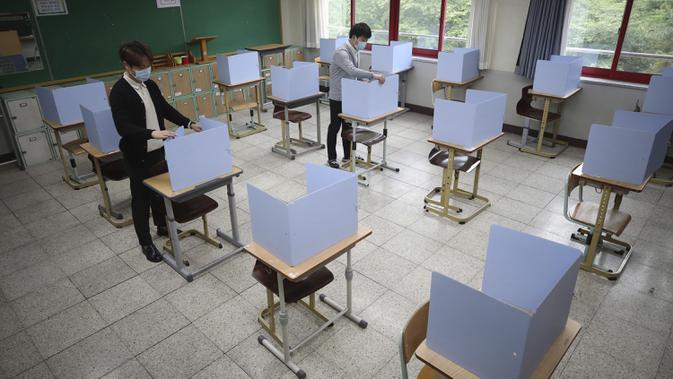 Para guru memeriksa pembatas pada meja siswa di Sekolah Menengah Putri Junghwa, Daegu, Korea Selatan, Selasa (19/5/2020). Sekolah-sekolah di Korea Selatan secara bertahap akan mulai dibuka pada 20 Mei 2020. (Kim Hyun-tae/Yonhap via AP)