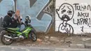 Pengendara motor berhenti di depan mural di Jalan Raya Citayam, Depok, Jawa Barat, Rabu (25/8/2021). Mural tersebut merupakan wujud ekspresi dari sejumlah seniman serta sebagai media penyampaian kritik sosial kepada pemerintah di tengah pandemi COVID-19. (Liputan6.com/Herman Zakharia)