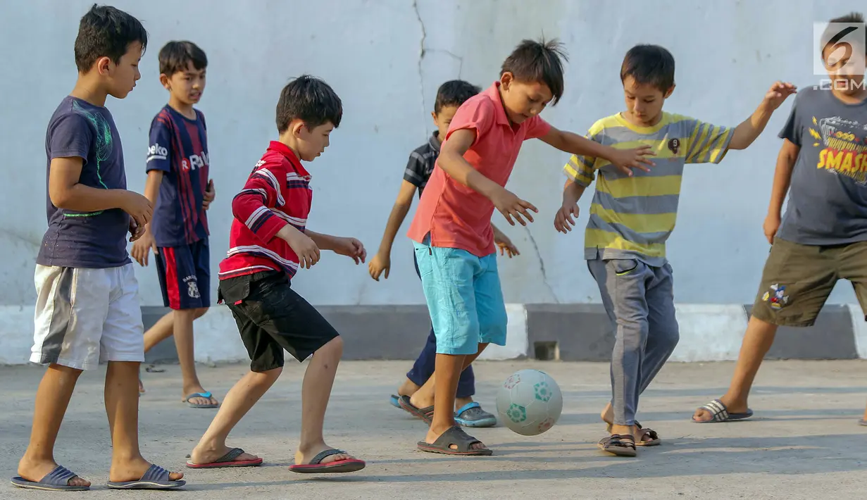 Anak-anak pencari suaka bermain sepak bola di halaman bekas Markas Kodim di Kalideres, Jakarta, Selasa (16/7/2019). Sebelumnya, para pencari suaka dari berbagai negara berkonfilk ini tinggal di pinggir jalan dan trotoar di kawasan Kebon Sirih, Jakarta. (Liputan6.com/Helmi Fithriansyah)