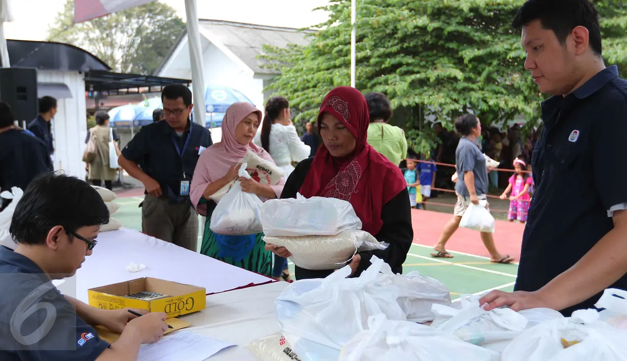 Seorang ibu saat membeli paket sembako murah yang diadakan Indosiar di Joglo, Jakarta, Senin (13/6). Paket berisikan 5 kg beras, 2 liter minyak goreng, 1 kg gula pasir dan 1 kg tepung terigu dijual Rp 30 ribu‎. (Liputan6.com/Angga Yuniar)