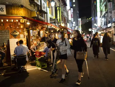 Sejumlah wanita berjalan sementara yang lain makan dan minum di restoran dan bar pada malam pertama pencabutan status darurat virus corona oleh pemerintah di Tokyo, Jepang, Jumat (1/10/2021). (AP Photo/Hiro Komae)