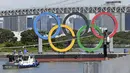 Para pekerja bersiap melepas cincin Olimpiade yang mengambang di air setelah Olimpiade Musim Panas 2020 berakhir pada 8 Agustus, di Tokyo, Rabu (11/8/2021).  Ajang yang digelar sejak 23 Juli itu akhirnya memastikan Kontingen Amerika Serikat (AS) menjadi juara umum. (Kyodo News via AP)