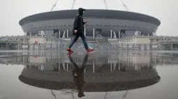 Seorang pria melintas di depan stadion sepak bola yang baru dibangun di Saint Petersburg di Rusia, Selasa (17/4). (AP Photo/Dmitri Lovetsky)