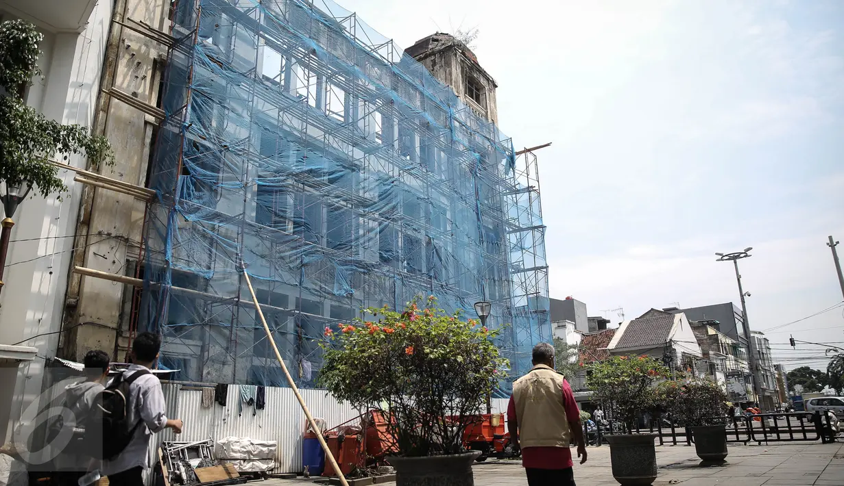 Sejumlah warga melintas di gedung yang sedang direvitalisasi dikawasan Kota Tua, Jakarta, Rabu (20/4). PT Jakarta Old Town Revitalisasi Corps mempercantik situs bekas bangunan peninggalan kolonial Belanda tersebut.(Liputan6.com/Faizal Fanani)