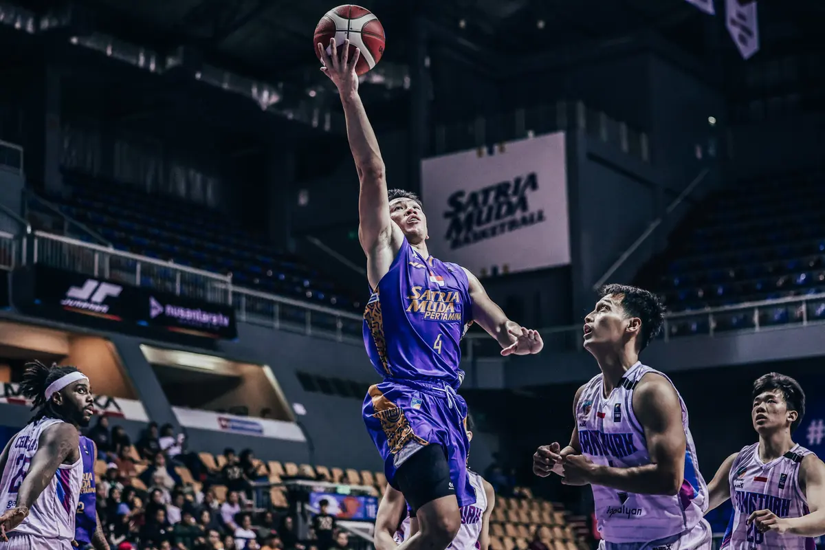 Pemain Satria Muda Abraham Damar Grahita memasukkan bola saat melawan Hangtuah di IBL 2025