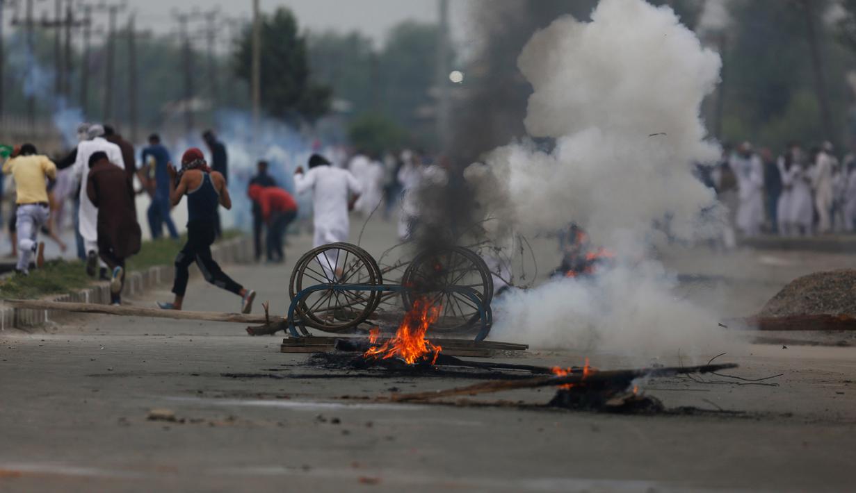 Para pengunjuk rasa membakar gerobak untuk memblokade jalan usai melakukan salat Idul Fitri di Srinagar, India (26/6). Mereka memprotes peraturan di India dan pro-kemerdekaan Kashmir. (AP Photo / Mukhtar Khan)