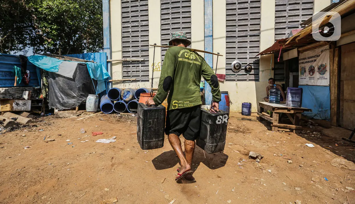 Penjual membawa jeriken berisi air bersih ke rumah pembeli di Kawasan Muara Angke, Jakarta Utara, Rabu (30/8/2023). (Liputan6.com/Faizal Fanani)