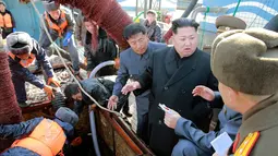 Pemimpin Korea Utara, Kim Jong-un menyimak keterangan pejabatnya saat menyaksikan langsung proses pemilahan ikan di stasiun perikanan di Pyongyang, Kamis (17/11). (REUTERS/KCNA)