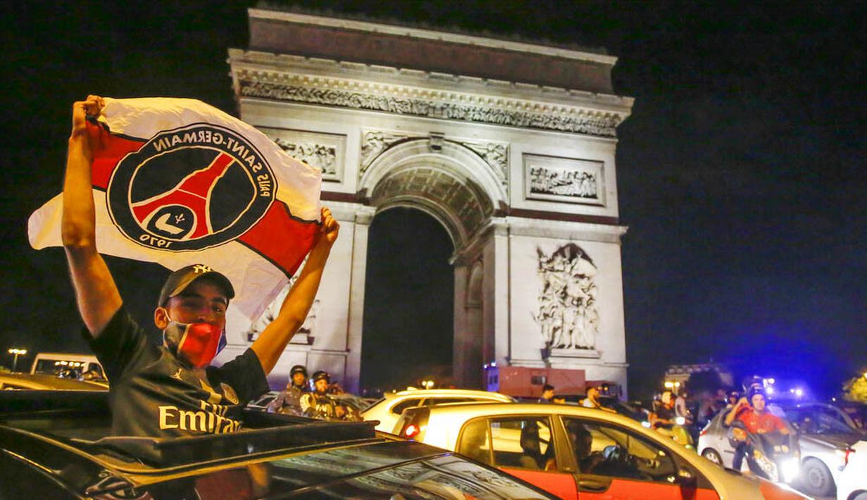 Seorang suporter mengibarkan bendera Paris Saint Germain (PSG) saat merayakan keberhasilan lolos ke final Liga Champions di Paris, Rabu (19/8/2020). Berkat kemenangan atas RB Leipzig, PSG untuk pertama kalinya berhasil lolos ke final Liga Champions. (AP/Michel Euler)
