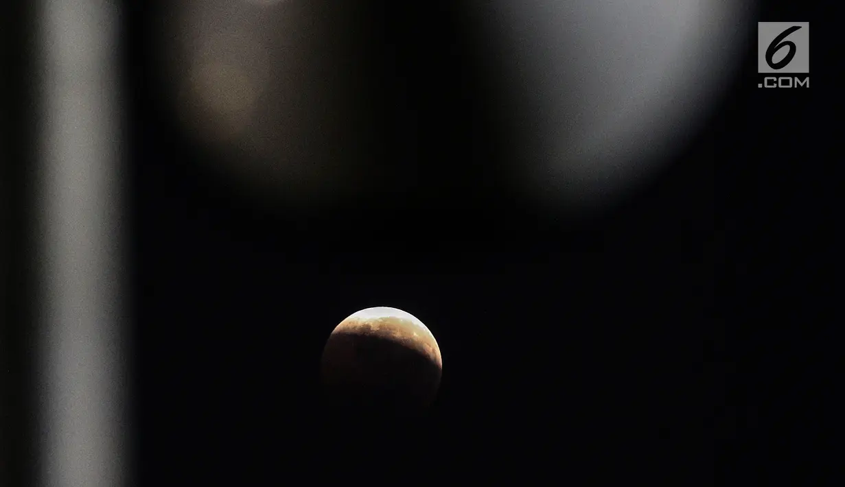 Foto fenomena gerhana bulan total di kota Jakarta, Sabtu (28/7). Gerhana bulan total "Micro Blood Moon" tersebut merupakan yang terlama pada abad ini dengan total waktu termasuk fase penumbra dan parsial selama enam jam lebih. (Liputan6.com/Johan Tallo)