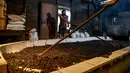 Para pekerja menyebarkan biji kopi robusta setelah disangrai secara tradisional di sebuah pabrik biji kopi kecil di Banda Aceh (14/11/2020). (AFP/Chaideer Mahyuddin)