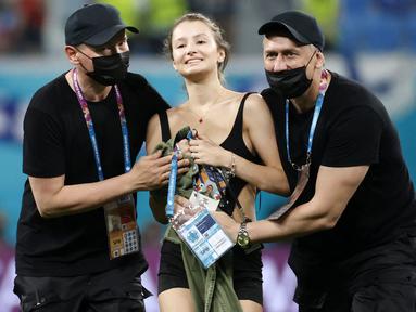 Petugas keamanan stadion menghentikan seorang penyusup lapangan wanita ketika pertandingan sepak bola Grup B UEFA EURO 2020 antara Finlandia melawan Belgia di Stadion Krestovsky, Saint Petersburg, Rusia, pada 21 Juni 2021. (AFP/Pool/Anatoly Maltsev)