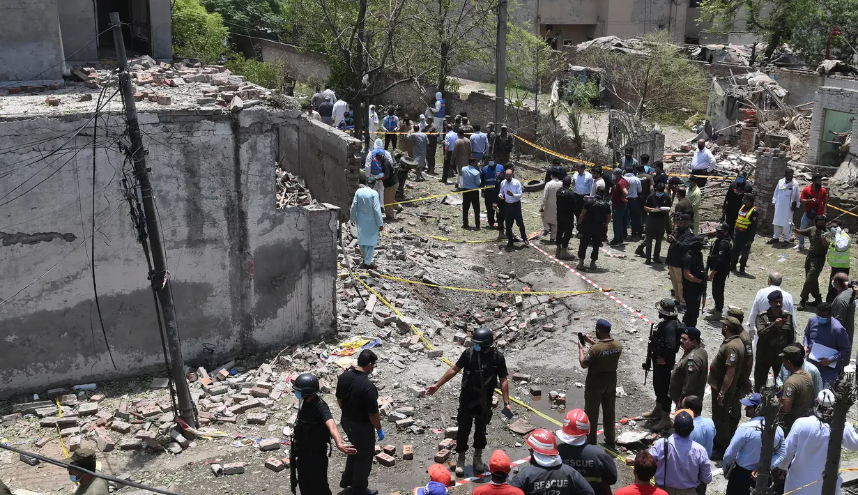 Petugas polisi, penyelidik, dan petugas penyelamat berkumpul di lokasi ledakan, di Lahore, Pakistan, Rabu (23/6/2021).  Saksi mata mengatakan intensitas ledakan itu sedemikian rupa sehingga jendela kaca rumah dan bangunan di dekatnya pecah.  (AFP/Arif Ali)