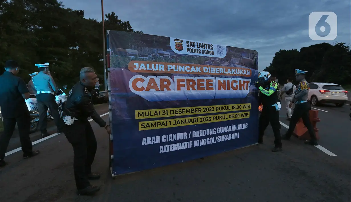 Petugas dari Polres Bogor memasang rambu penutupan jalan di pintu keluar Tol Gadog, Bogor, Sabtu (31/12/2022). Penutupan jalan jalur Puncak Bogor untuk gelaran Car Free Night dimulai sejak pukul 18.00 WIBdan dibuka kembali esok pagi pukul 06.00 WIB. (merdeka.com/Arie Basuki)
