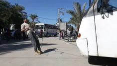 Mohamed Barka, pria yang dijuluki "Super Hero" asal Palestina menarik sebuah bus dengan gigi dalam aksinya di Deir Al-Balah, Gaza Tengah, Kamis (4/2). (MOHAMMED ABED/AFP)