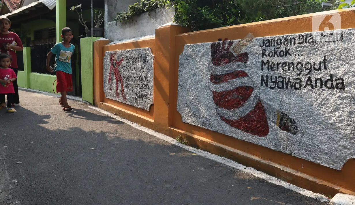 Warga melintasi mural bertema kawasan bebas asap rokok di lingkungan RW 06 Kelurahan Kayu Manis, Matraman, Jakarta, Jumat (8/10/2021). Beberapa titik pada kawasan tersebut juga terdapat mural-mural tentang pemberitahuan serta peringatan untuk tidak dan berhenti merokok (Liputan6.com/Herman Zakharia)