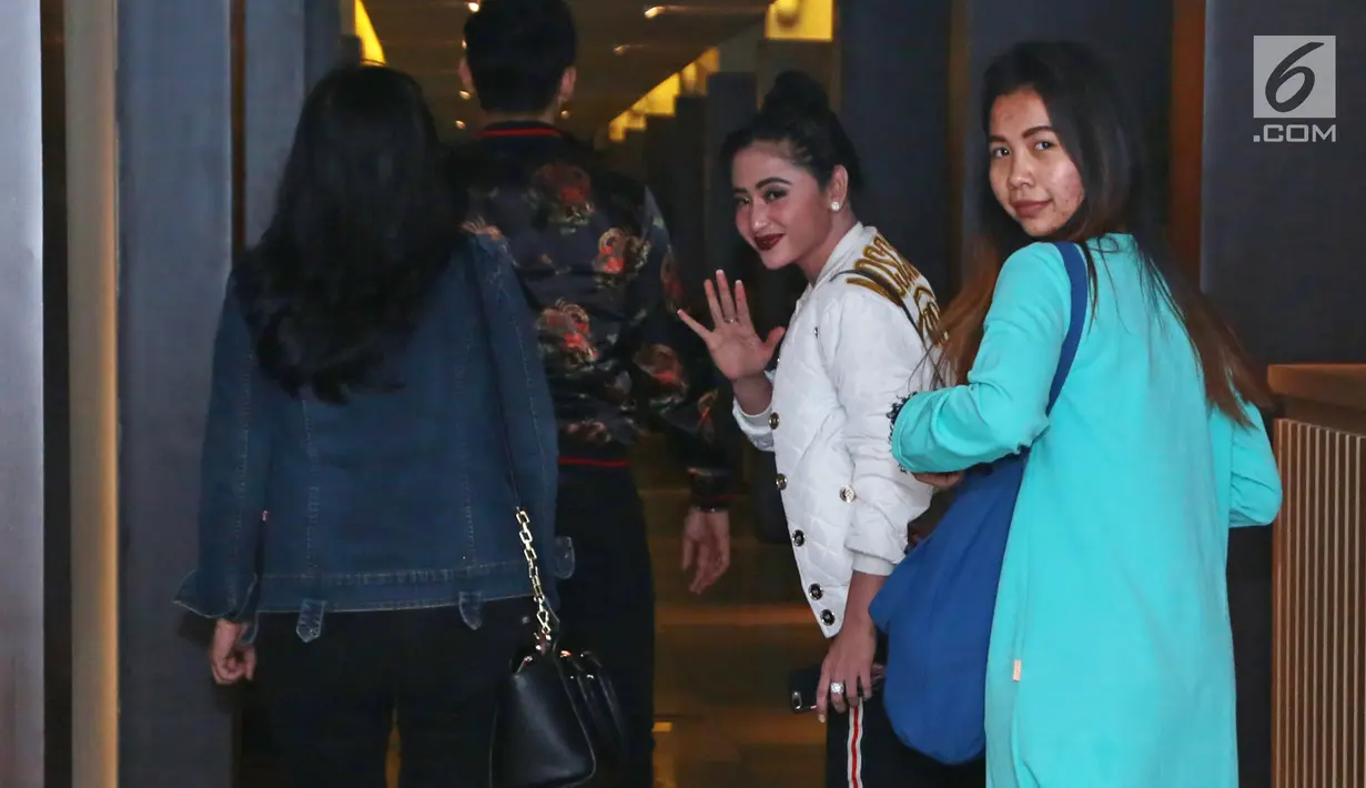 Dewi Persik melambaikan tangan sembari berjalan menuju Sentra Pelayanan Kepolisian Terpadu (SPKT), Polda Metro Jaya, Senin (4/12). Dewi melapor balik petugas TransJakarta, Harry Maulana Saputra atas pencemaran nama baik. (Liputan6.com/Herman Zakharia)