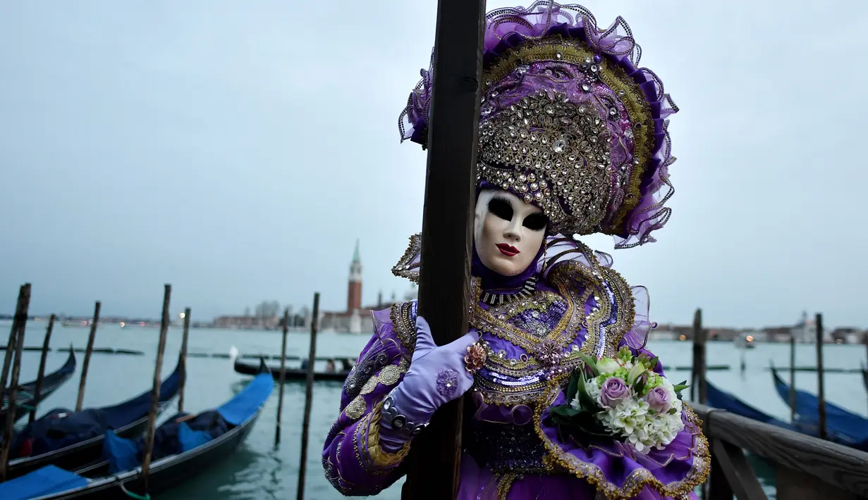 Peserta mengenakan kostum dan topeng berpose untuk difoto saat berpartisipasi dalam Karnaval Venesia di Italia (27/1). Ciri khas dari karnaval ini adalah Topeng Venesia yang terbuat dari kulit atau akrilik. (AFP Photo/Filippo Monteforte)