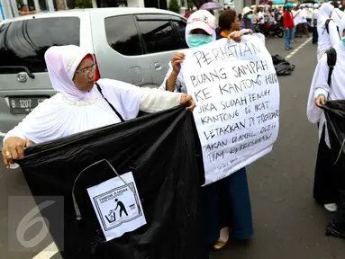 Sejumlah relawan membawa kantong plastik besar dan spanduk bertuliskan "Throw A HOAX, Here Please" di tengah aksi damai 4 November di Jakarta, Jumat (4/11). Mereka mengumpulkan sampah yang dibuang anggota ormas. (Liputan6.com/Faizal Fanani)