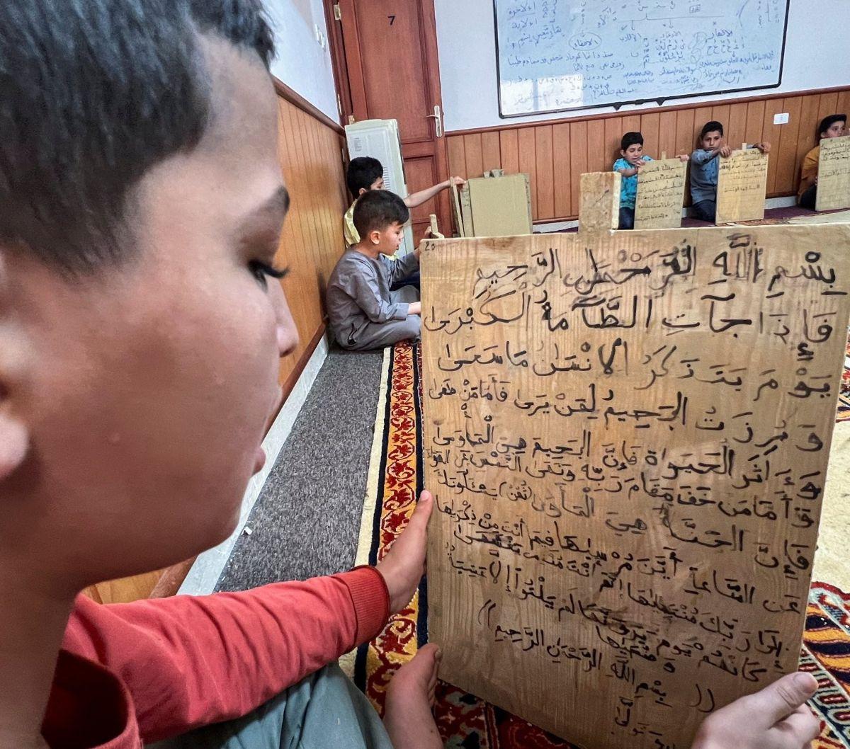Di sebuah masjid di Tripoli, Libya, sejumlah anak masih belajar membaca dan menulis ayat-ayat Alquran menggunakan cara yang unik, yaitu papan kayu selama bulan suci Ramadhan pada tanggal 3 April 2023. Foto: REUTERS / Ayman al-Sahili<br>