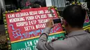 Petugas mengambil gambar karangan bunga berisi dukungan pada KPK di halaman Gedung KPK, Jakarta, Senin (20/11). Karangan bunga tersebut sebagai bentuk dukungan masyarakat kepada KPK terhadap pemberantasan kasus korupsi e-KTP. (Liputan6.com/Faizal Fanani)